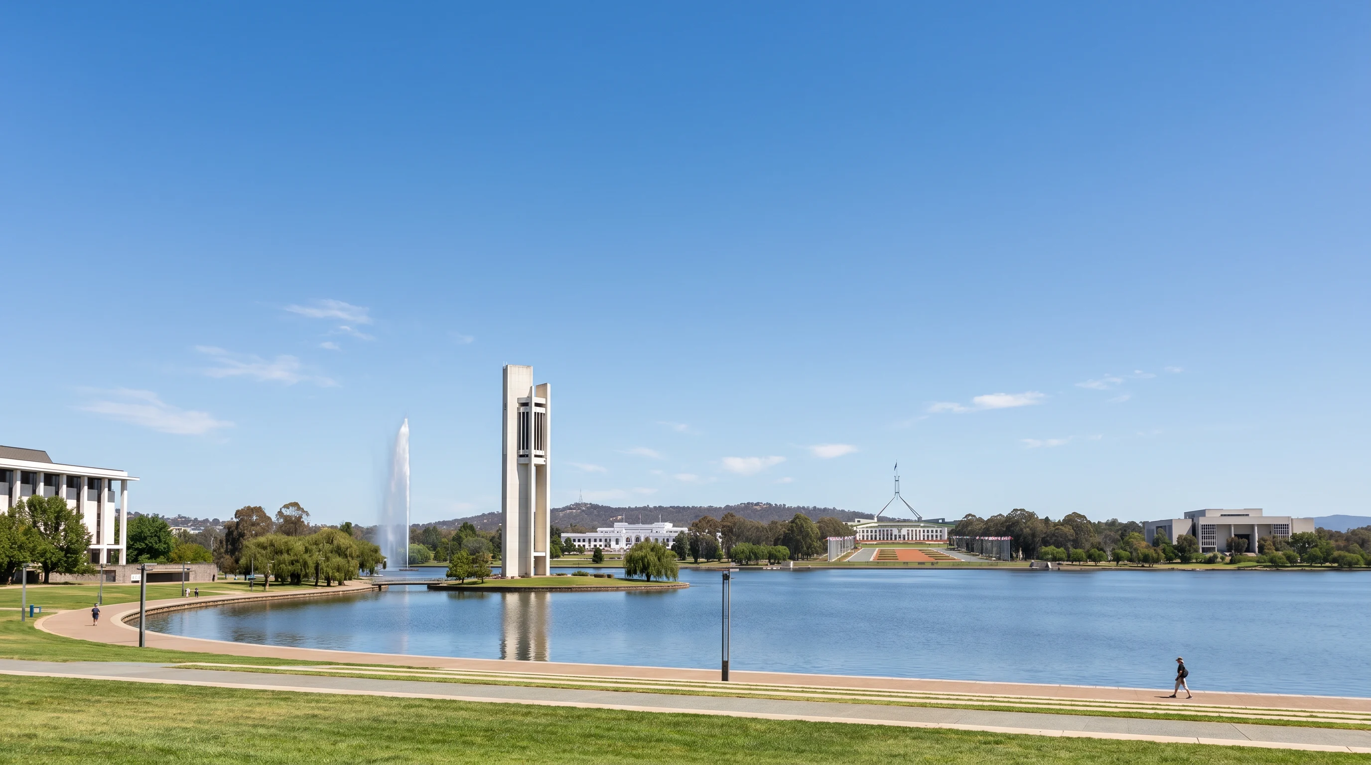 Lake Burley Griffin waterfront with Canberra's planned Parliamentary Triangle visible across the water, a wide clear sky above